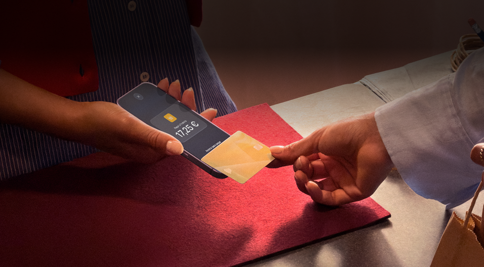 Una mano acerca una tarjeta de crédito a un iPhone para pagar una compra