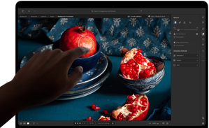 MacBook Pro con pantalla PROLED XDR con una imagen con frutas, cuencos de cerámica y tejidos azules, una mano se acerca a la pantalla para interactuar con la obra de arte